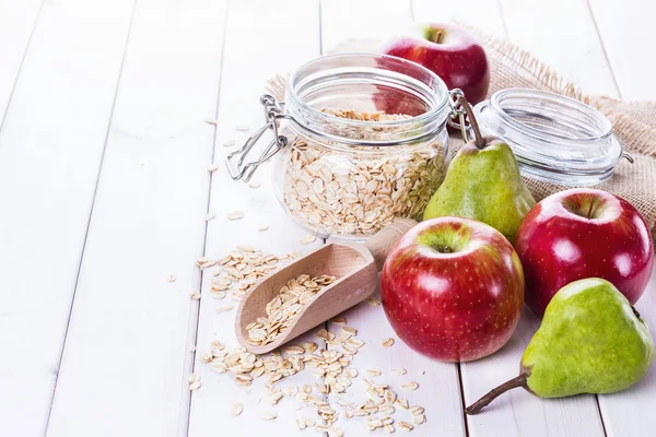 Fresh fruits and rolled oats over white background — Stock Photo, Image