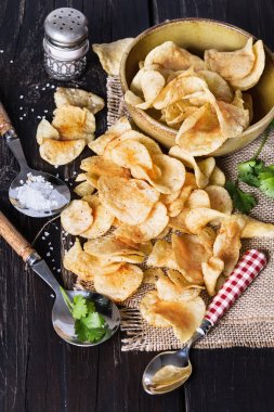Homemade potato chips over dark wooden background 
