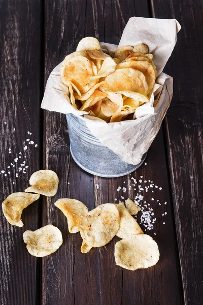 Potato chips over dark wooden background — Stock Photo, Image