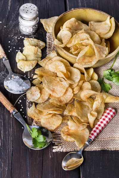 Potato chips over dark wooden background — Stock Photo, Image