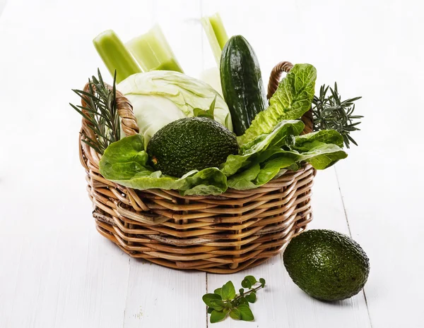 Green vegetables and herbs in a woven basket — Stock Photo, Image
