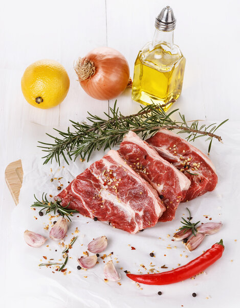Red meat, vegetables and spices over white background