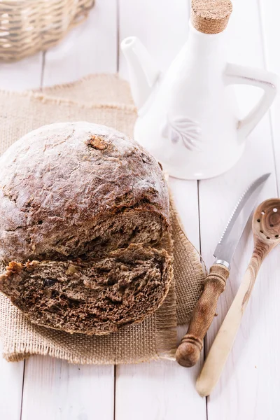 Pan de centeno recién horneado mazorca y utensilios de cocina sobre fondo de madera —  Fotos de Stock