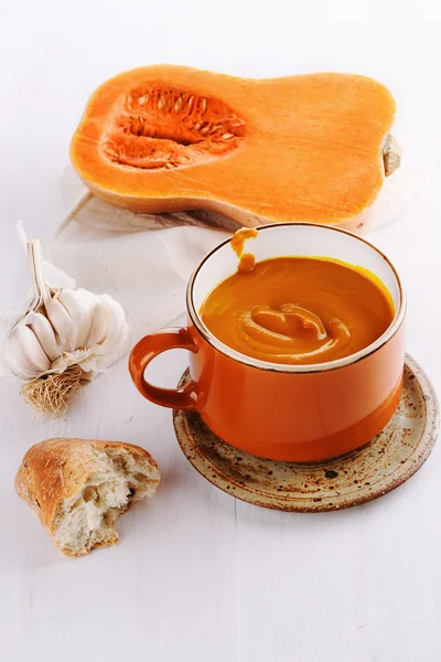 Soupe de citrouille, pain et ail sur fond de bois blanc — Photo