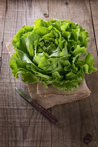 Butter lettuce on a burlap cloth over rustic background — Stock Photo, Image