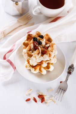 Homemade waffles with nuts and berries over white wooden backgro