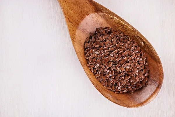 Linseed in a wooden spoon over white background — Stock Fotó