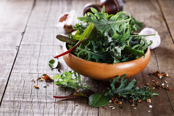 Leafy green mix over rustic wooden background — Stock Photo, Image