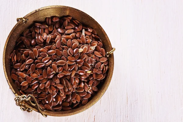 Lijnzaad dat gebruikt wordt in een gewicht schotel over witte houten achtergrond — Stockfoto