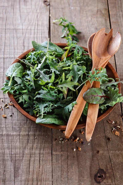 Leafy green mix over rustic wooden background — Stock Photo, Image