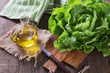 Butter lettuce and oil over wooden rustic background