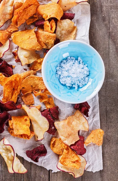 Chips de legumes saudáveis e sal em um fundo rústico — Fotografia de Stock