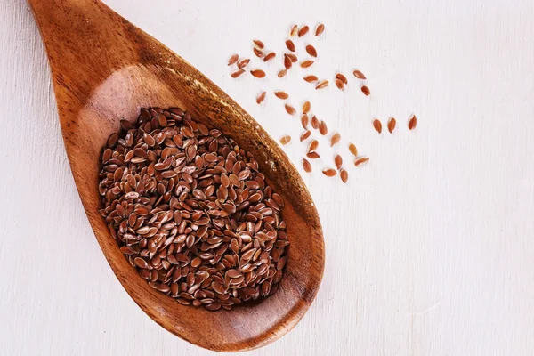 Linseed in a wooden spoon over white background — Stock Fotó