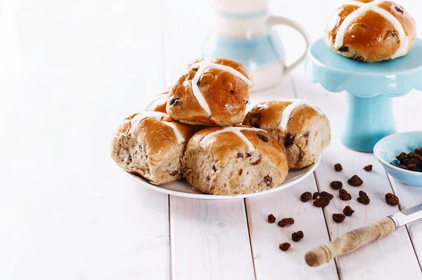 Bollos cruzados de Pascua sobre un fondo de madera blanca — Foto de Stock