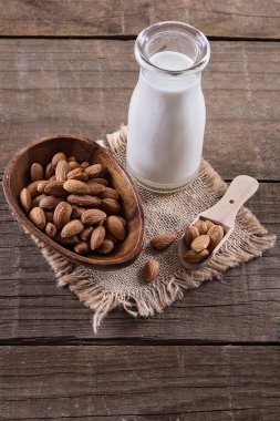 Şişe badem sütü ve rustik ahşap arka plan üzerinde fındık