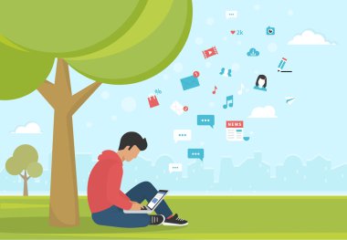 Genç adam parkta bir ağacın altında oturan ve laptop ile çalışma