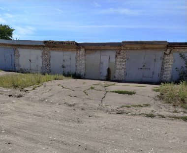 Kırsal kesimdeki tozlu yolun yakınındaki eski garajlar ve ambarlar. Köy ya da küçük kasaba manzarası.