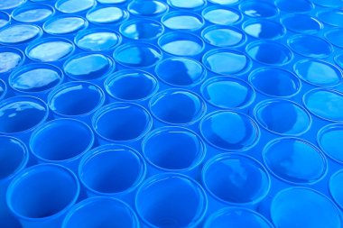 Mavi plastik bardaklarda temiz su. Soyut arkaplan.