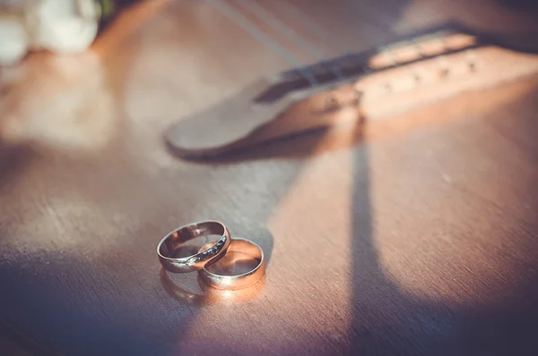 Snubní prsteny ležící na kytaru Stock Obrázky