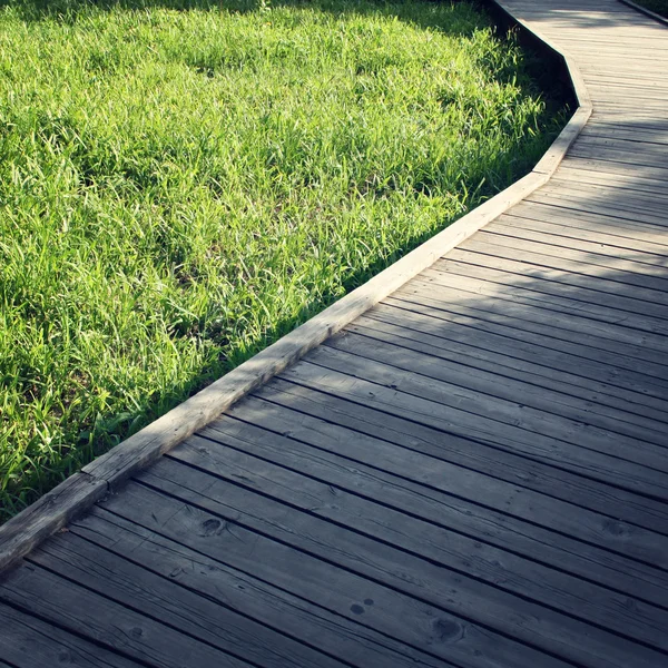 Sentiero in legno in un parco primaverile. Foto invecchiata . — Foto Stock