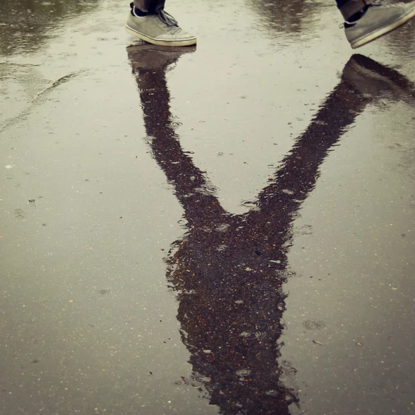 Réflexion dans l'asphalte humide. Marcher adolescent . — Photo