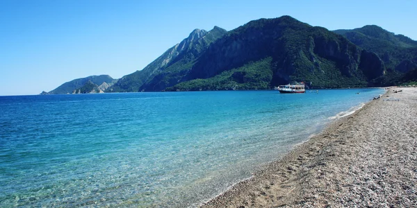 View on Cirali Bay. Tourist boat in the sea. Aged photo.