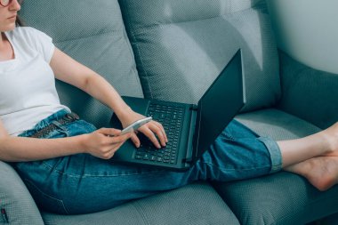 Genç iş kadını ya da evden uzakta çalışan serbest çalışan, hem laptop hem de akıllı telefon kullanan. Genç bir kadın mobil uygulama ve arama motorları kullanarak online alışveriş yapıyor. Çevrimiçi eğitim veya WFH kavramı