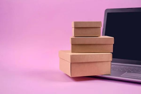 Передній перегляд на комп'ютері ноутбука та упаковка представлені коробки на пастельно-рожевому тлі з копіювальним простором для тексту. Сезонний продаж, чорна п'ятниця та концепція кіберпонеділка. Інтернет-магазини. Вибірковий фокус — стокове фото
