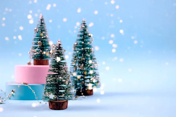 Composición de moda de Navidad y Año Nuevo con árboles de Navidad, decoraciones y luces bokeh sobre fondo azul pastel con copyspace. Enfoque selectivo, lugar para el texto — Foto de Stock