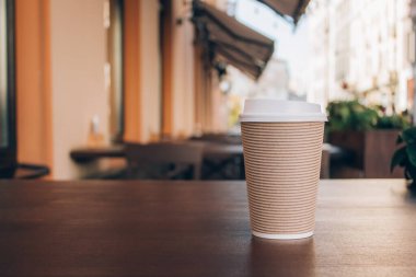 Fotokopi makinesi gibi arka planda bulanık kafesi olan ahşap masanın üzerinde duran kahve fincanı görüntüsü. Geri dönüşümlü kağıt bardağa koymak için kahve.