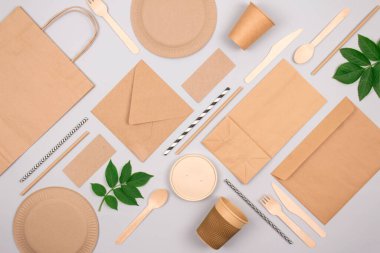 Çevre dostu sofra takımı olan düz kompozisyon - açık gri arka planda kraft kağıt gıda ambalajı. Sokak yiyecekleri ambalajı, geri dönüşümlü kağıtlar ve sıfır atık ambalaj konsepti. Model