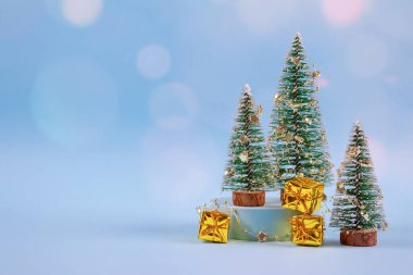 Christmas and New Year composition with New Year tree, golden present boxes, decorations and bokeh lights on pastel blue background with copyspace. Selective focus, place for your text clipart