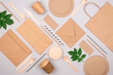 Çevre dostu sofra takımı olan düz kompozisyon - açık gri arka planda kraft kağıt gıda ambalajı. Sokak yiyecekleri ambalajı, geri dönüşümlü kağıtlar ve sıfır atık ambalaj konsepti. Model
