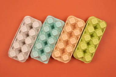 Turuncu arka planda çok renkli organik yumurta tepsileri ve metin için kopyalanmış boşluk. Biyolojik çözünebilir ve gübrelenebilir kağıt paketleme. Atık ayıklama, ev konseptinde çöp ayıklama
