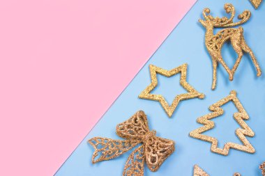 Noel ve Yeni Yıl kompozisyonu - Pastel mavi ve pembe arka planda altın süslemeler. Metnin için telif alanı olan şenlikli çerçeve. Seçici odak