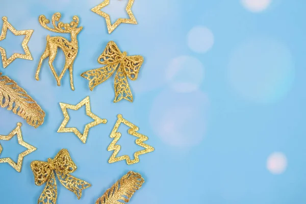 Composição de Natal e Ano Novo - decorações de ouro em fundo azul pastel com luzes de bokeh. Quadro festivo com copyspace para o seu texto. Foco seletivo — Fotografia de Stock