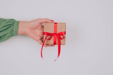 Kırmızı fiyonklu hediye kutusuyla süslenmiş kadınlar el ele tutuşur. Noel tatili, yeni yıl ya da doğum günü kutlaması konsepti. Noel için aile hediyeleri hazırlıyor, ona hediyeler hazırlıyor.