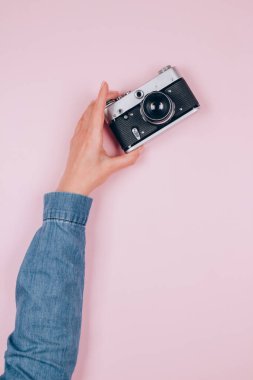 Pembe arka planda eski bir fotoğraf makinesini tutan bir kadın ve metin için fotokopi alanı var. Eski moda fotoğrafçılık, online fotoğrafçılık okulu konsepti. Seçici odak, dikey bileşim