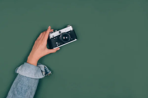Eine weibliche Hand hält eine alte Retro-Fotokamera auf grünem Hintergrund mit Kopierraum für Text. Trendige Vintage-Fotografie, Online-Fotografie Schulkonzept. Selektiver Fokus — Stockfoto