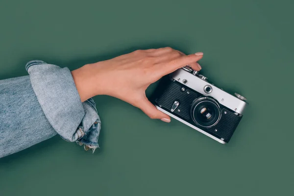 Nahaufnahme einer weiblichen Hand, die eine alte Retro-Fotokamera auf grünem Hintergrund mit Kopierraum für Text hält. Trendige Vintage-Fotografie, Online-Fotografie Schulkonzept. Selektiver Fokus — Stockfoto
