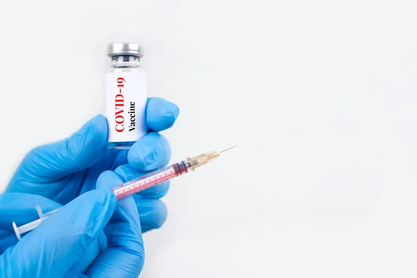 Dokter atau ilmuwan yang memegang dosis vial vaksin COVID-19 dengan jarum suntik terhadap latar belakang putih dengan ruang fotokopi untuk teks - pencegahan coronavirus, konsep vaksinasi global. Fokus selektif — Stok Foto