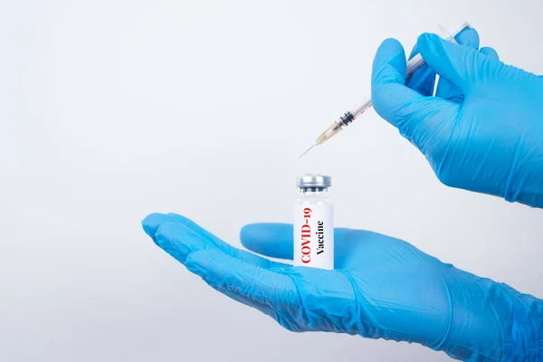 Dokter wanita atau ilmuwan yang memegang dosis vial vaksin COVID-19 dengan jarum suntik terhadap latar belakang putih dengan ruang fotokopi - Pencegahan coronavirus, konsep vaksinasi global. Fokus selektif — Stok Foto