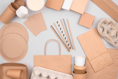 Çevre dostu sofra takımı - açık gri arka planda Kraft kağıt gıda ambalajı. Sokak yemekleri ve fast food ambalajları - barlar, tabaklar, pipetler, kaplar ve kese kağıtları. Düz konum, telif alanı