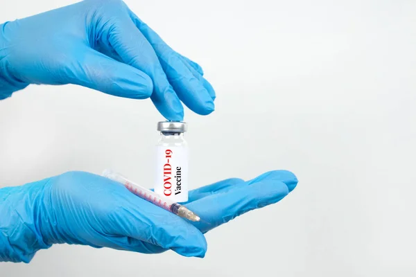 Female scientist or doctor hands holding vial dose of COVID-19 vaccine with syringe against white background with copy space - prevention coronavirus, global vaccination concept. Selective focus — Stock Photo, Image