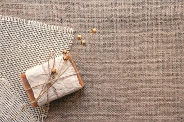 El yapımı doğal sabun çubuğunun üst görüntüsü. Kırsal kumaş arka planında keten çiçeği ve fotokopi alanı. Doğal besinler ve organik yağlarla yapılan spa ürünleri. Cilt bakımı kavramı