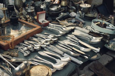 Antiques on flea market or festival, aged vintage silver cultery - spoons, knifes, forks, and other vintage things. Collectibles memorabilia and garage sale concept clipart