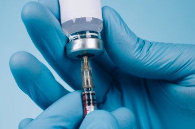 Küresel aşı kavramı. Doktor ya da bilim adamı, şırıngayla şırınganın yaygın dozunu fotokopi alanındaki mavi arka planda tutuyor. Koronavirüsü önleme. Seçici odak, biçimlendirme resmi
