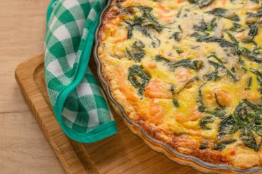 Somon balığı veya deniz ürünleri ve ıspanaklı kiş turtası, ahşap masa arkaplanlı ev yapımı tart, fotokopi alanı, yakın görüş. Seçici odak