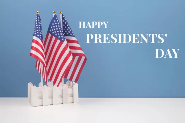 Creative composition with USA flags on white table with blue wall background - Presidents Day 2021 concept