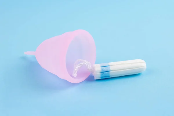 Farklı kadın hijyen ürünleri - pembe adet bardağı ve mavi arka planda fotokopi alanı olan tampon. Kadın sağlığı ve hijyen kavramı, alternatif hijyen ürünleri, seçici odaklanma — Stok fotoğraf